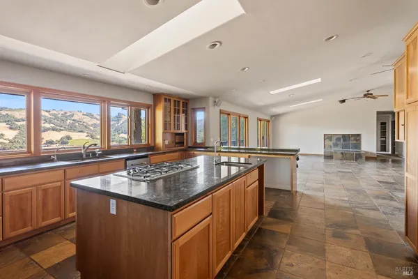 a kitchen with stainless steel appliances granite countertop a sink a counter top space and a large window