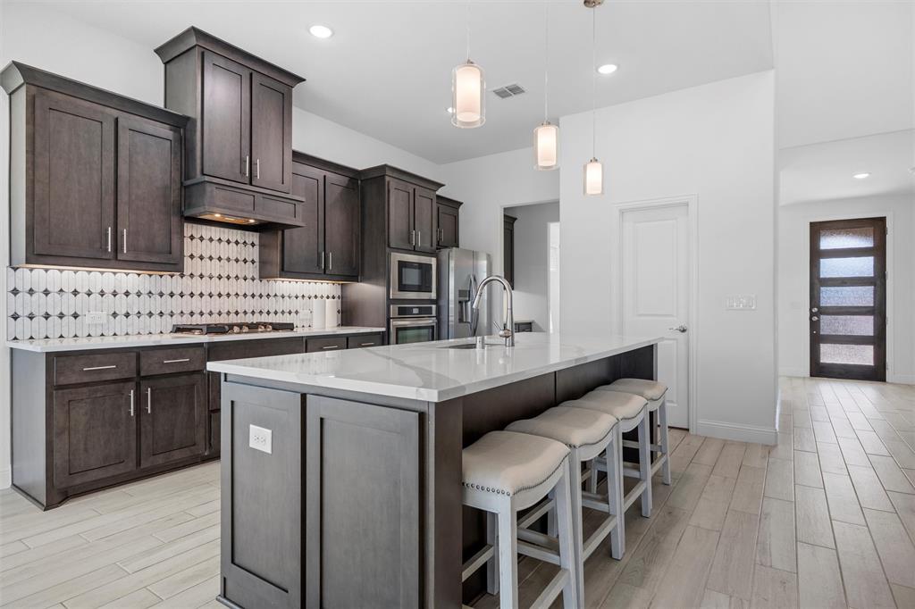 753 Truchas Avenue Forney, TX 75126 - Photo 7 of 29 a kitchen with stainless steel appliances kitchen island granite countertop a sink and cabinets