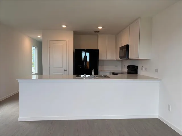 a view of kitchen with stainless steel appliances granite countertop white cabinets and refrigerator
