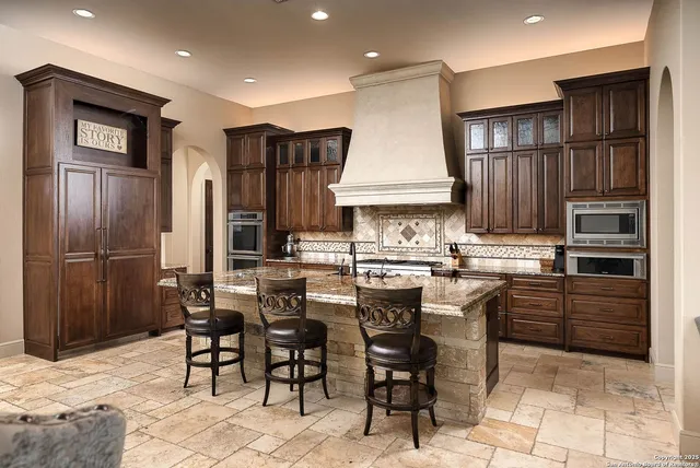 a kitchen with stainless steel appliances granite countertop a sink a stove and a refrigerator