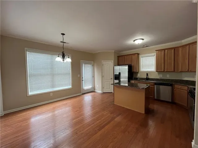 a open kitchen with kitchen island granite countertop wooden floors white cabinets and stainless steel appliances
