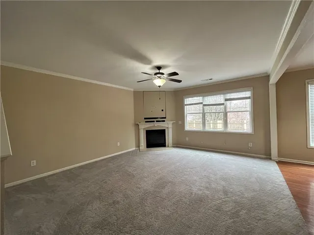 an empty room with a fireplace and chandelier fan