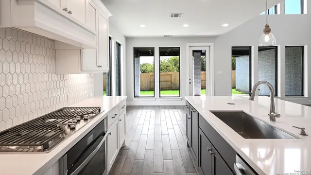 a kitchen with large windows a sink and a stove