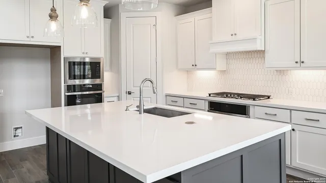 a kitchen with kitchen island a stove a sink and white cabinets