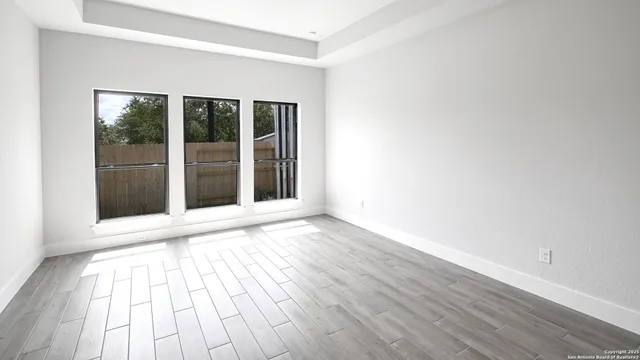 a view of an empty room with wooden floor and a window
