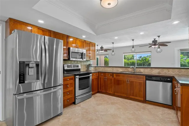 a kitchen with stainless steel appliances granite countertop a refrigerator a stove top oven and sink
