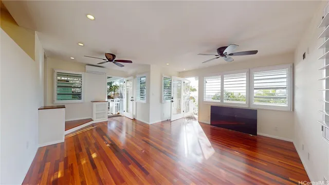 a view of an empty room with wooden floor and a window