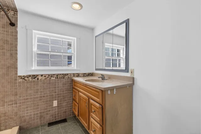 a bathroom with a granite countertop sink and a window