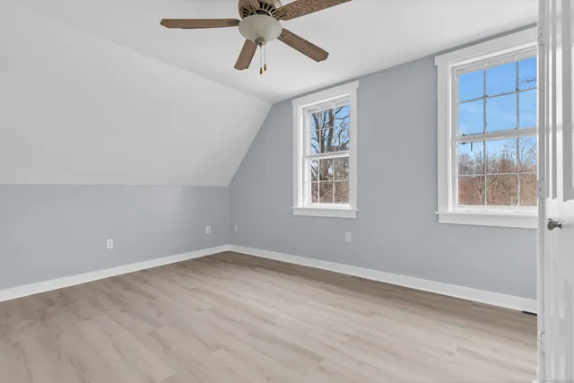 an empty room with wooden floor fan and windows
