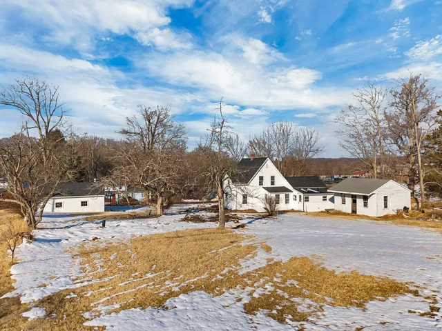 a view of a white house with a yard covered in snow