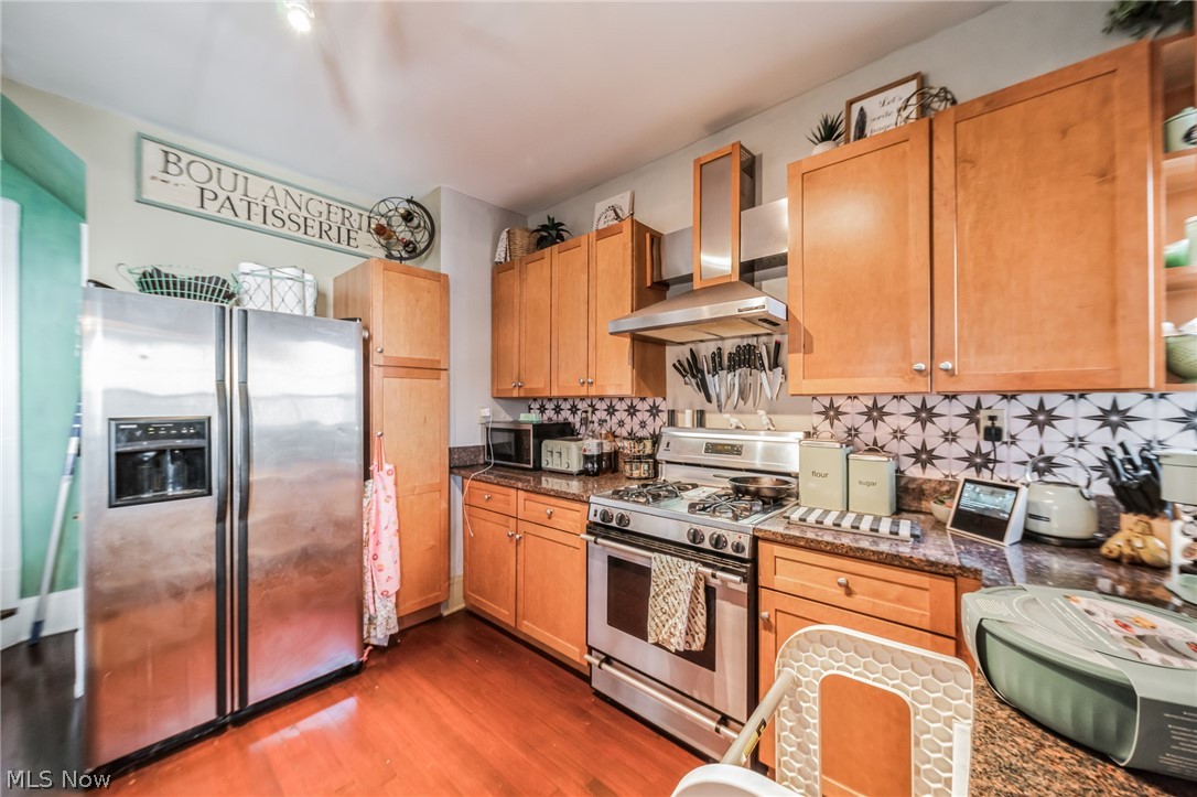 14432 Superior Road Cleveland, OH 44118 - Photo 19 of 24 Kitchen with stainless steel appliances, tasteful backsplash, wall chimney range hood, and dark hardwood / wood-style floors