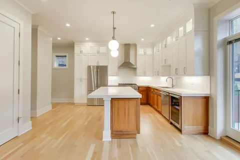 a kitchen with stainless steel appliances kitchen island a refrigerator and a wooden floors