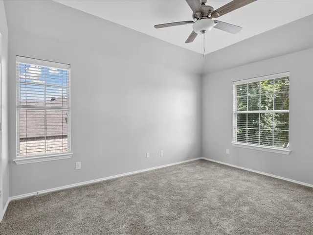 an empty room with a window and a fan