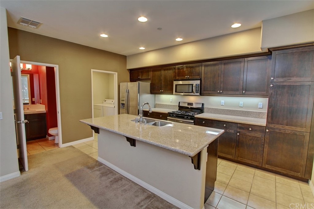 16073 Gables Loop Whittier, CA 90603 - Photo 8 of 31 a kitchen with stainless steel appliances a refrigerator sink stove microwave and cabinets