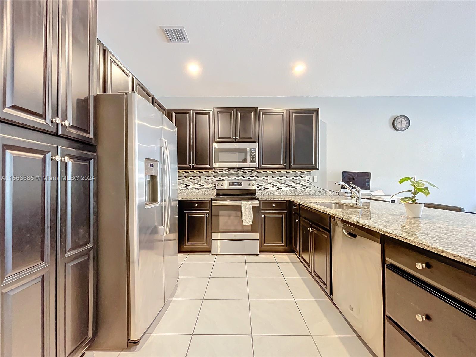 10888 Southwest 235th Lane Homestead, FL 33032 - Photo 11 of 36 a kitchen with stainless steel appliances granite countertop a refrigerator and a sink
