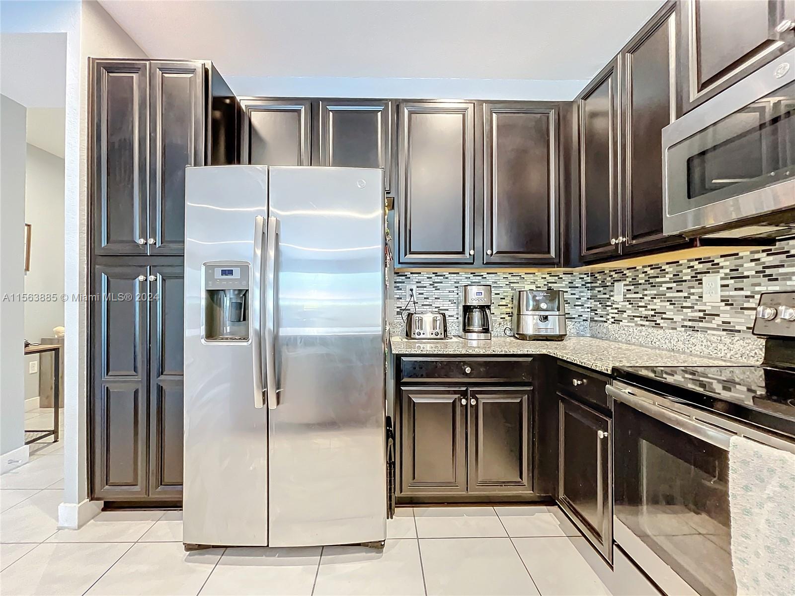 10888 Southwest 235th Lane Homestead, FL 33032 - Photo 13 of 36 a kitchen with stainless steel appliances granite countertop a refrigerator and a stove top oven