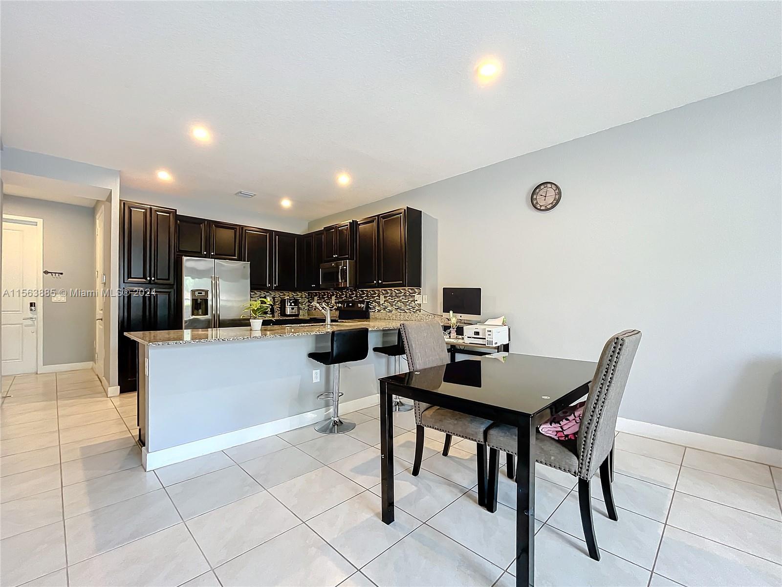10888 Southwest 235th Lane Homestead, FL 33032 - Photo 17 of 36 a kitchen with stainless steel appliances kitchen island granite countertop a sink and a refrigerator