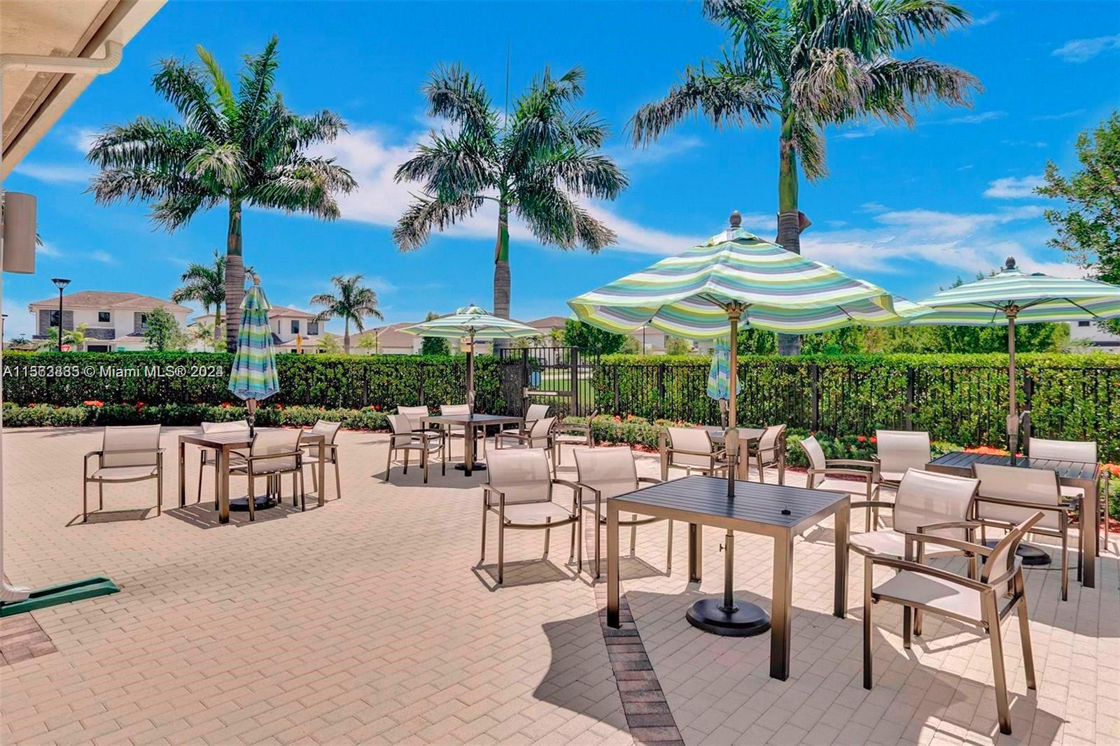 10888 Southwest 235th Lane Homestead, FL 33032 - Photo 34 of 36 a view of patio with a table and chairs under an umbrella with palm trees