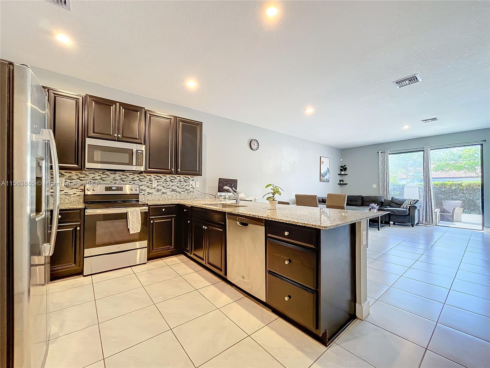 10888 Southwest 235th Lane Homestead, FL 33032 - Photo 10 of 36 a kitchen with stainless steel appliances a sink counter space cabinets and a large window