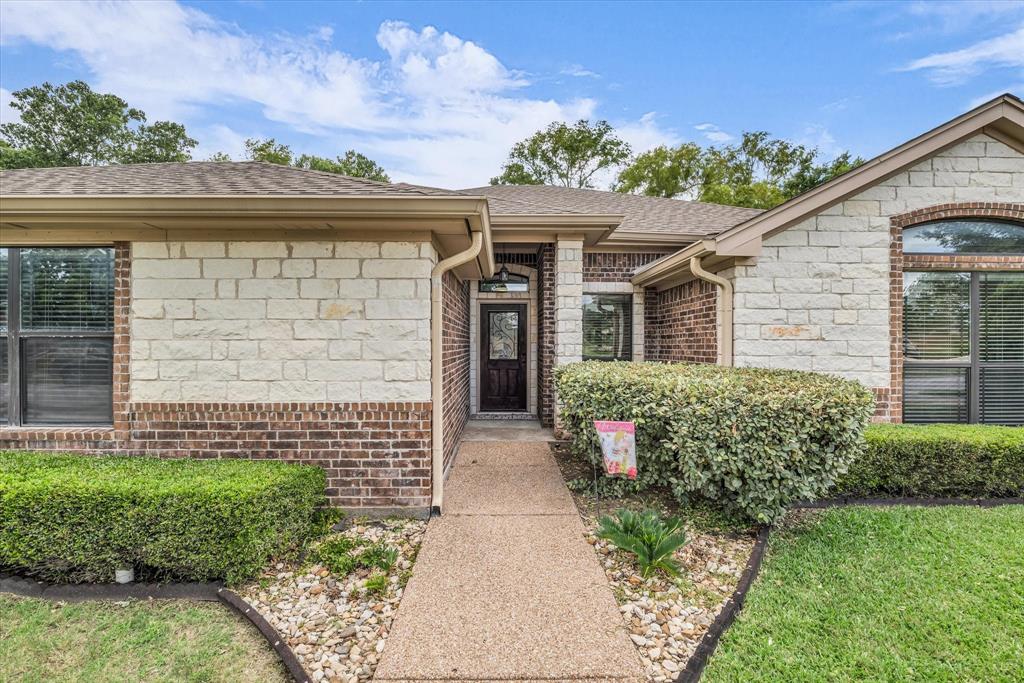 814 Springdale Circle Lorena, TX 76655 - Photo 4 of 37 Front exterior featuring a brick and stone facade, arched window, dark wood entry door with glass inserts, concrete pathway, and structured landscaping