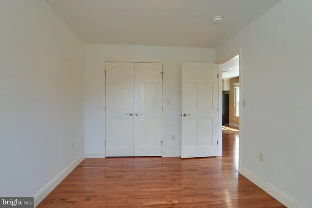 a view of an empty room with wooden floor and closet
