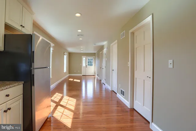 a view of a hallway with wooden floor and a bathroom
