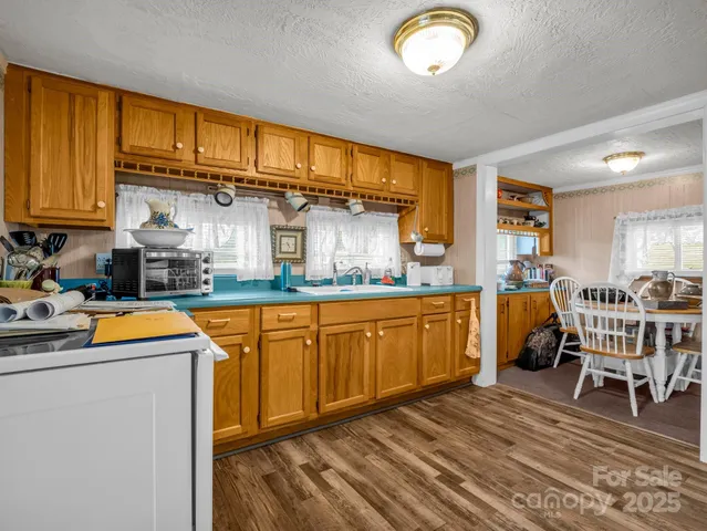 a kitchen with stainless steel appliances granite countertop a sink dishwasher stove and cabinets with wooden floor