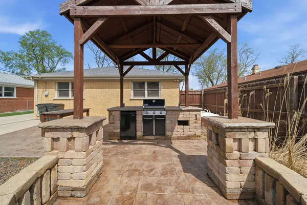 a view of a patio with table and chairs a barbeque with wooden floor and fence