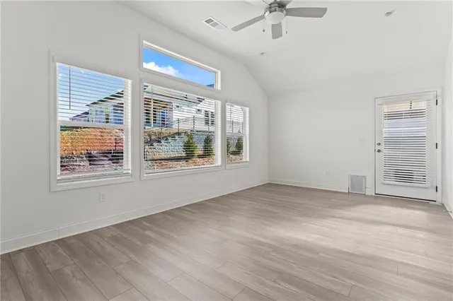 a view of an empty room with a window and wooden floor