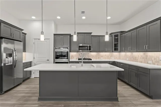 a large kitchen with kitchen island a large counter top stainless steel appliances and cabinets