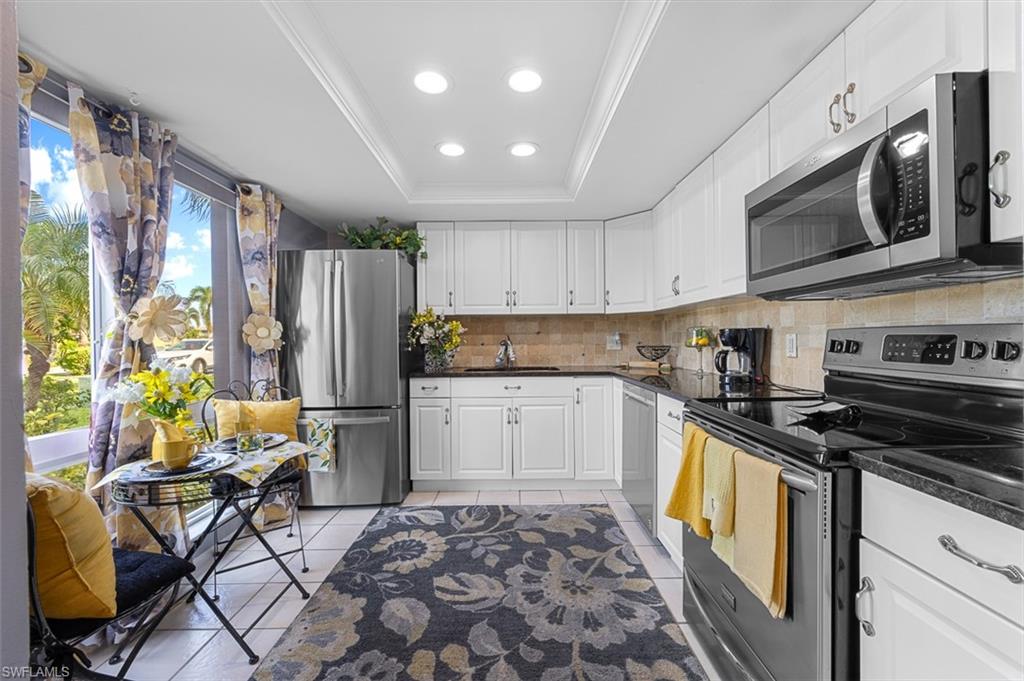 197 Harrison Road, Unit 3 Naples, FL 34112 - Photo 2 of 14 Kitchen featuring stainless steel appliances, a raised ceiling, white cabinetry, decorative backsplash, and recessed lighting
