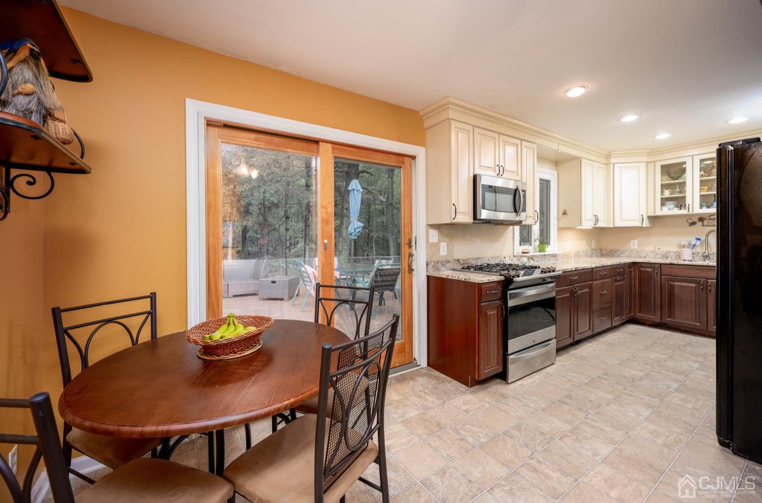 45 Stockton Road Kendall Park, NJ 08824 - Photo 14 of 30 a kitchen with stainless steel appliances granite countertop a stove a refrigerator a sink a dining table and chairs with wooden floor