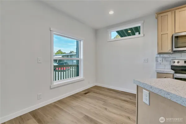 a view of a kitchen and an empty room with wooden floor and a window
