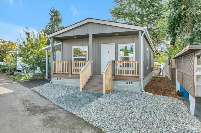 a view of a house with a yard plants and large tree