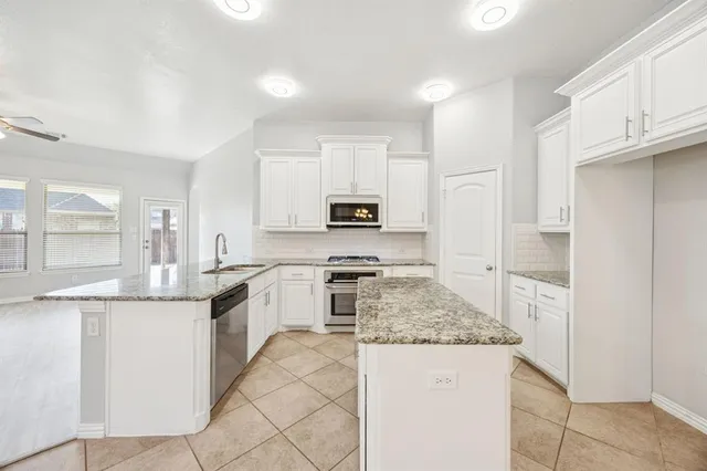 a kitchen with granite countertop stainless steel appliances and white cabinets