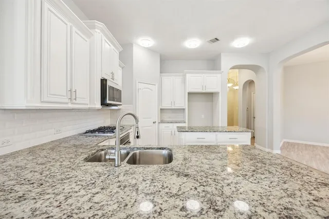 a kitchen with granite countertop a sink a stove and cabinets