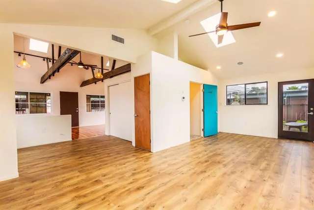 a view of an empty room with wooden floor and a ceiling fan