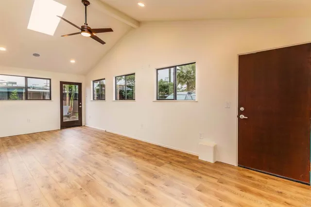a view of an empty room with window and a kitchen