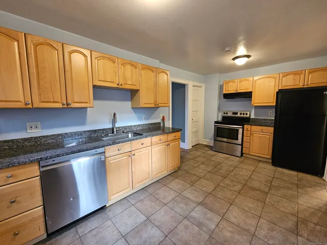 a kitchen with stainless steel appliances granite countertop a stove a sink and a refrigerator