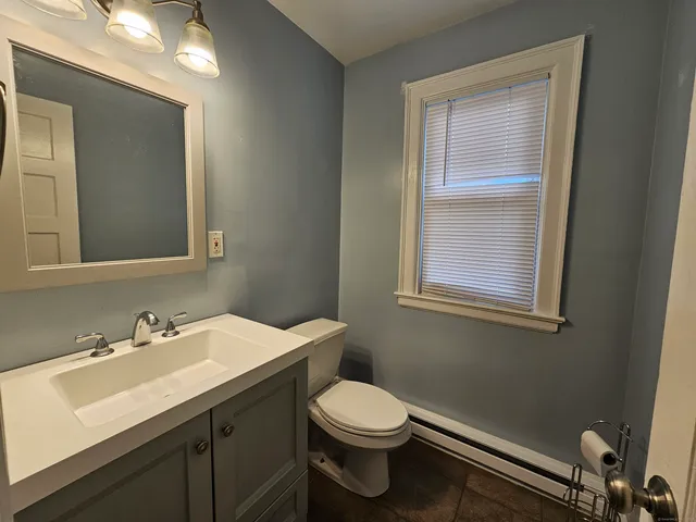 a bathroom with a toilet a sink a mirror and window