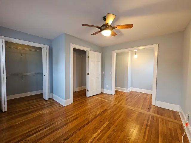 a view of empty room with wooden floor and fan
