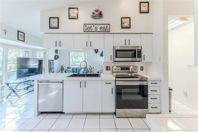 a kitchen with stainless steel appliances kitchen island granite countertop a refrigerator and a sink