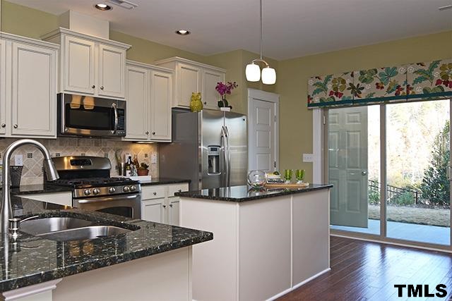 7900 Allscott Way Raleigh, NC 27612 - Photo 2 of 12 a kitchen with kitchen island granite countertop a stove top oven a sink a counter space and cabinets
