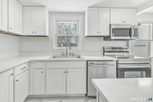 a kitchen with white cabinets and sink