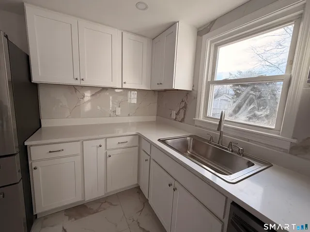 a kitchen with white cabinets appliances a sink and a window
