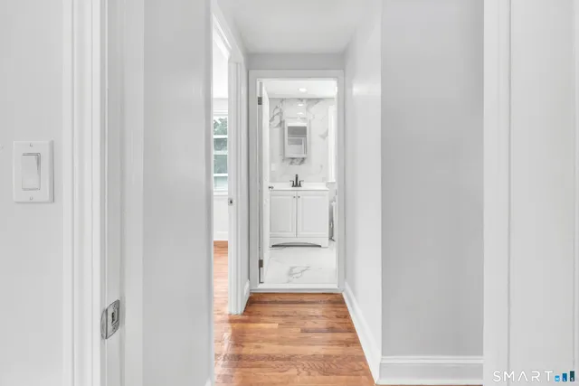 a view of a hallway with wooden floor and a bathroom