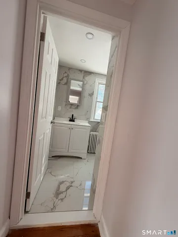 a view of a hallway with wooden floor and cabinet