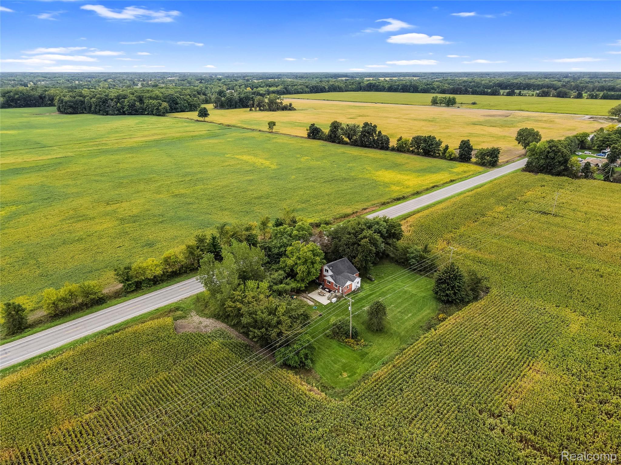 8330 Baldwin Road Gaines, MI 48436 - Photo 26 of 27 Expansive rural setting with a residential structure, surrounded by cultivated fields and mature trees