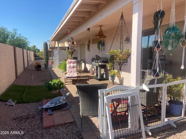 a view of a patio with table and chairs potted plants and floor to ceiling window