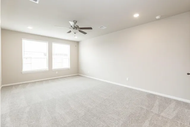 an empty room with windows and ceiling fan